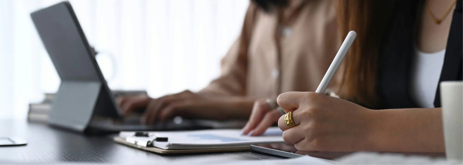 Zwei Personen arbeiten gemeinsam an einem Laptop und Dokumenten.